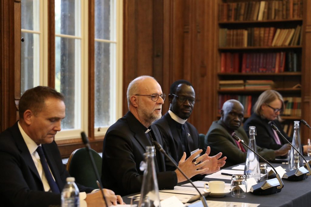 A church leader addresses the meeting at Lambeth Palace while other participants listen