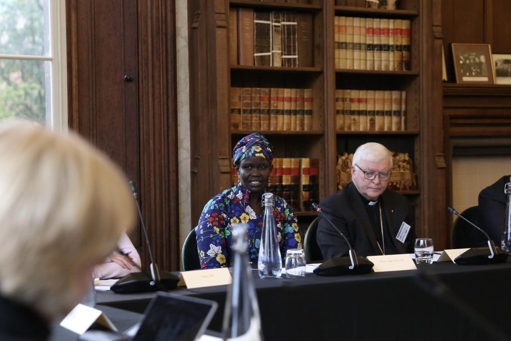 Angelina Jial speaking at a meeting table in the library at Lambeth Palace, with a church leader seated beside her