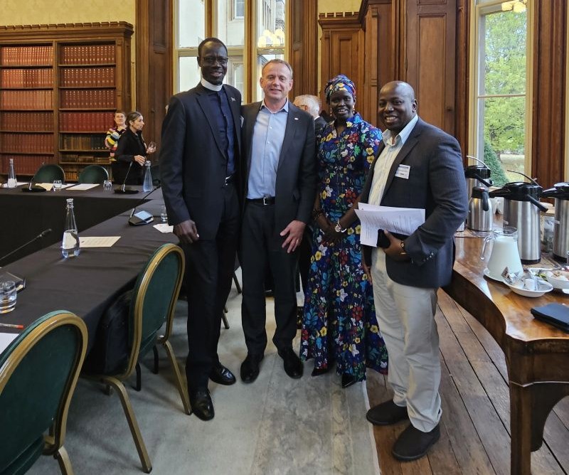 Angelina Jial standing with three fellow participants in a wood-panelled meeting room at Lambeth Palace
