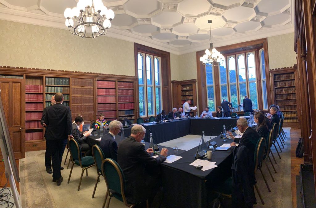 Wide view of participants seated around a U-shaped table in a library at Lambeth Palace