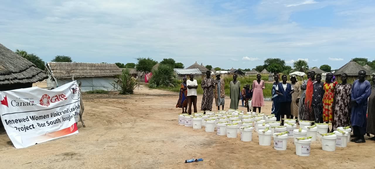 Women and men stand behind the WASH items distributed by HRSS in Bor, Jonglei State.