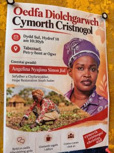 Welsh-language poster from Christian Aid Cymru inviting people to the Christian Aid Thanksgiving Service on Sunday 18 October at 10:30am at Tabernacl, Bridgend, with guest Angelina Nyajima Simon Jial, Founder and Director of Hope Restoration South Sudan.